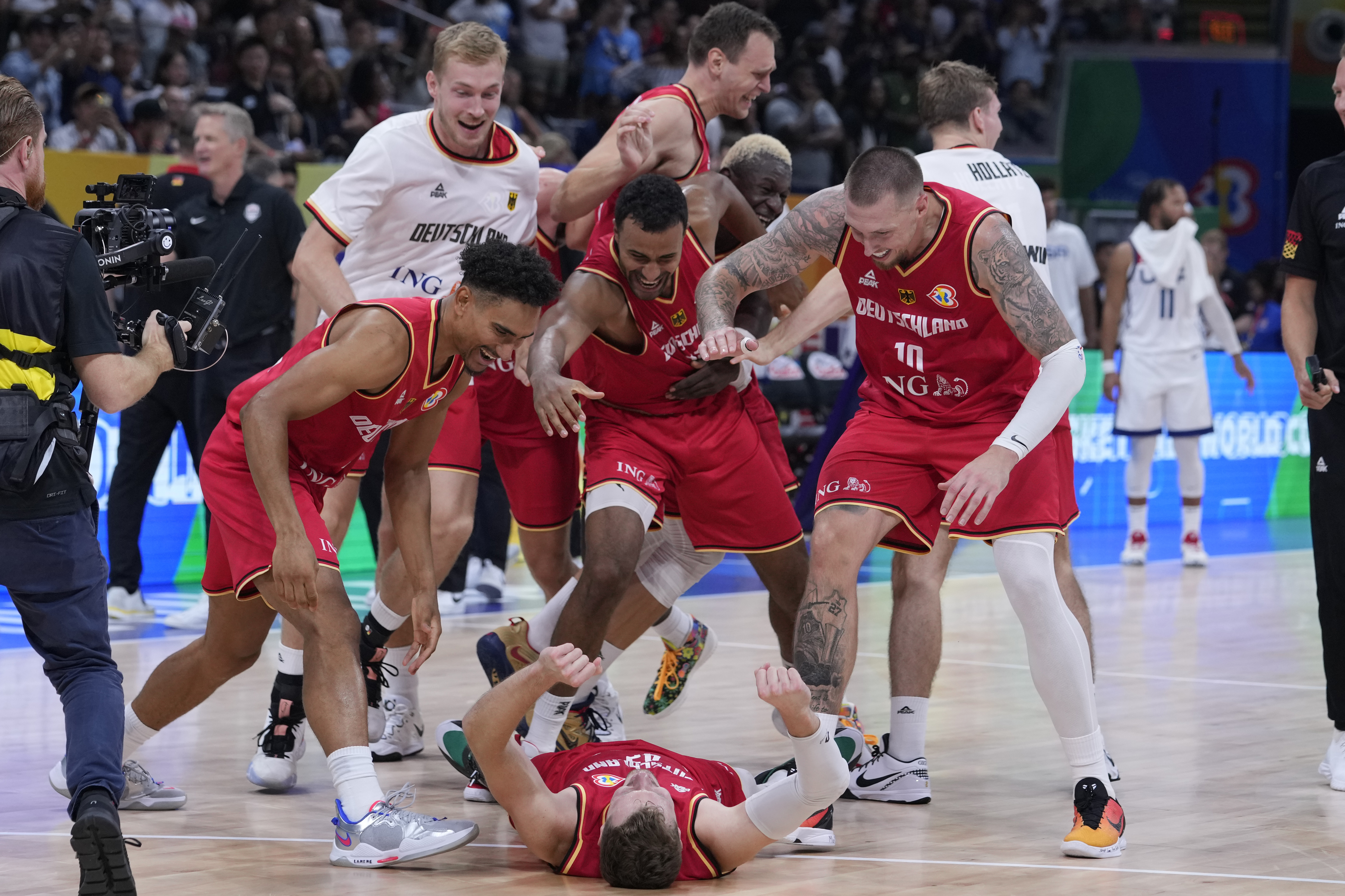 Germany guard Andreas Obst lays on the ground as teammates celebrates after winning against the United States in a Basketball World Cup semi final game in Manila, Philippines, Friday, Sept. 8, 2023. (AP Photo/Michael Conroy)